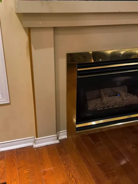 Before: gas fireplace in a painted wood surround with brass trim